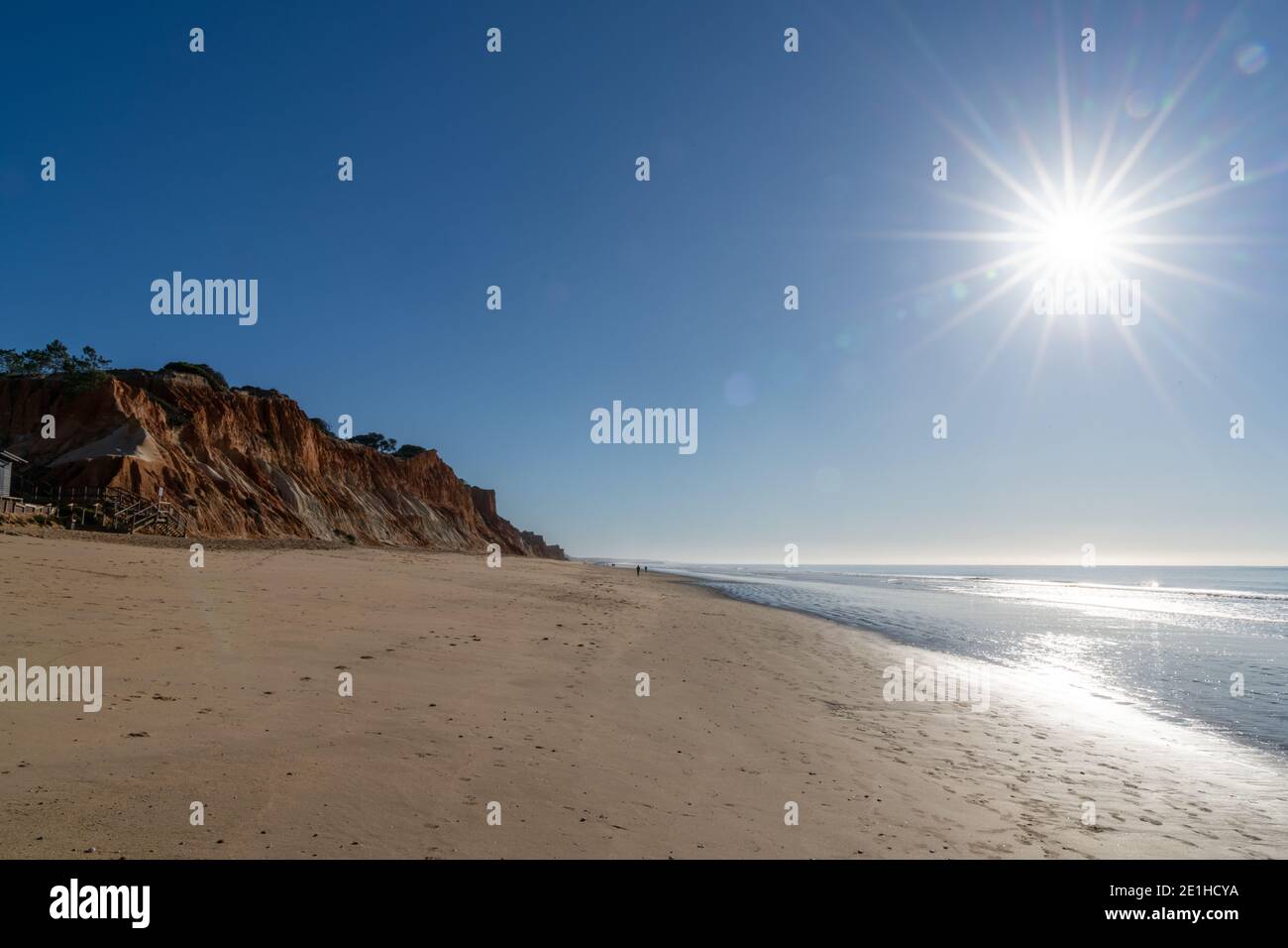 Une vue sur une grande plage de sable doré vide avec falaises de sable colorées par une journée ensoleillée Banque D'Images