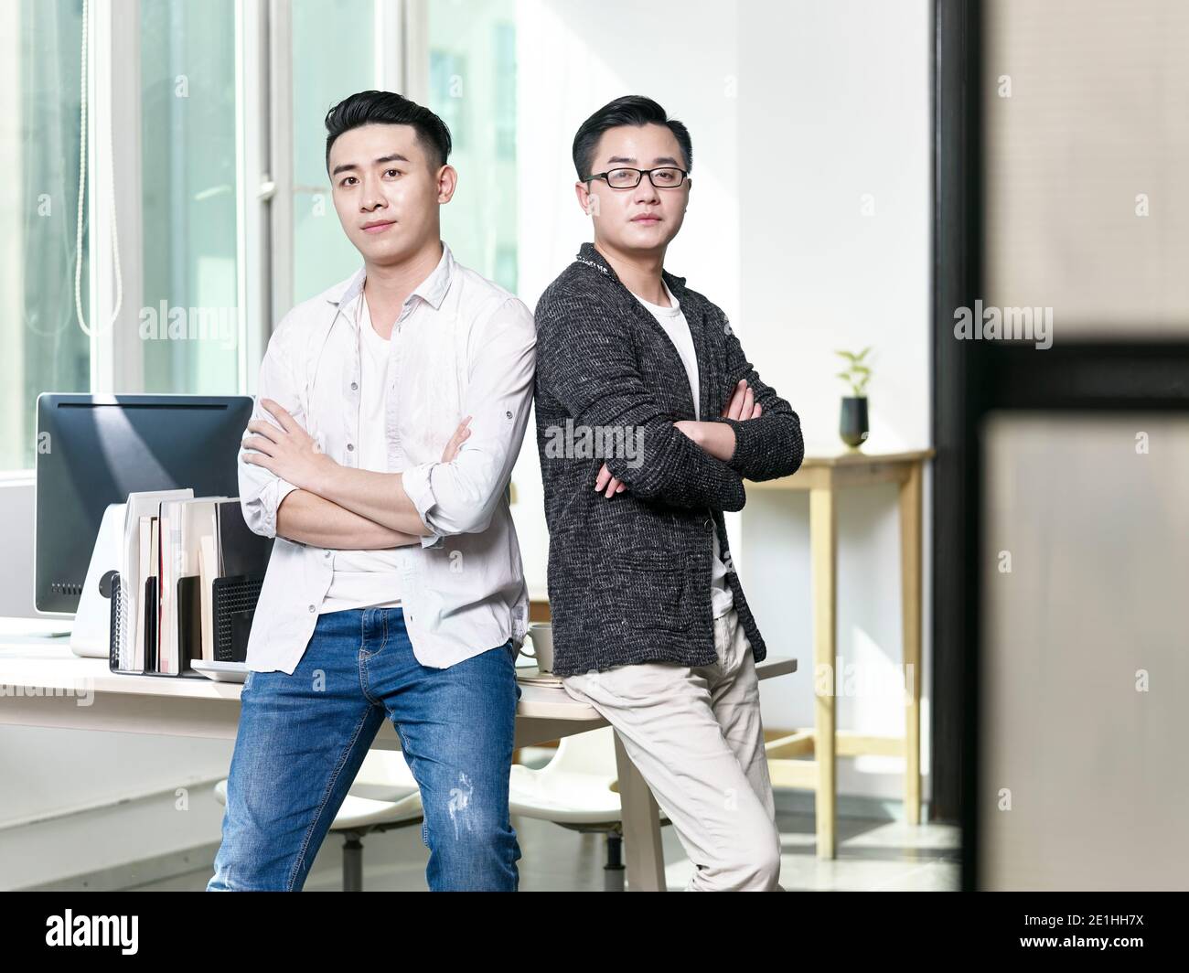 portrait de deux jeunes hommes d'affaires asiatiques qui se posent à nouveau de retour au bureau en regardant la caméra Banque D'Images