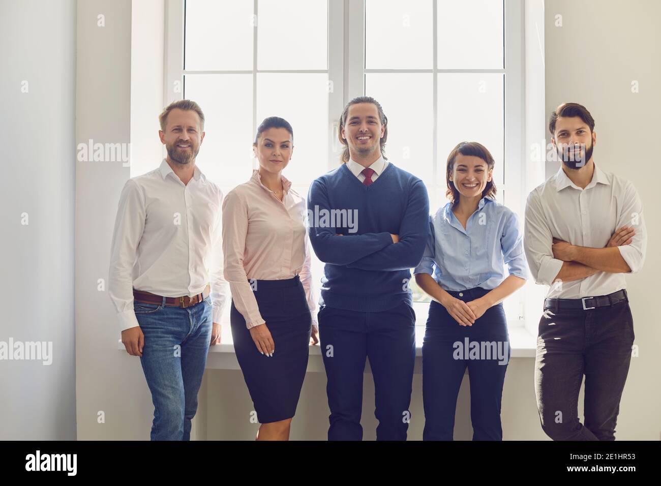 Portrait d'une équipe d'affaires créative réussie regardant l'appareil photo et souriant près de la fenêtre. Banque D'Images