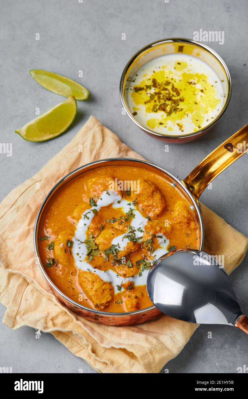 Murgh Makhani ou beurre poulet dans un bol en cuivre sur une table en béton gris. Plat de cuisine indienne avec viande de poulet et masala crémeux. Cuisine asiatique et méa Banque D'Images