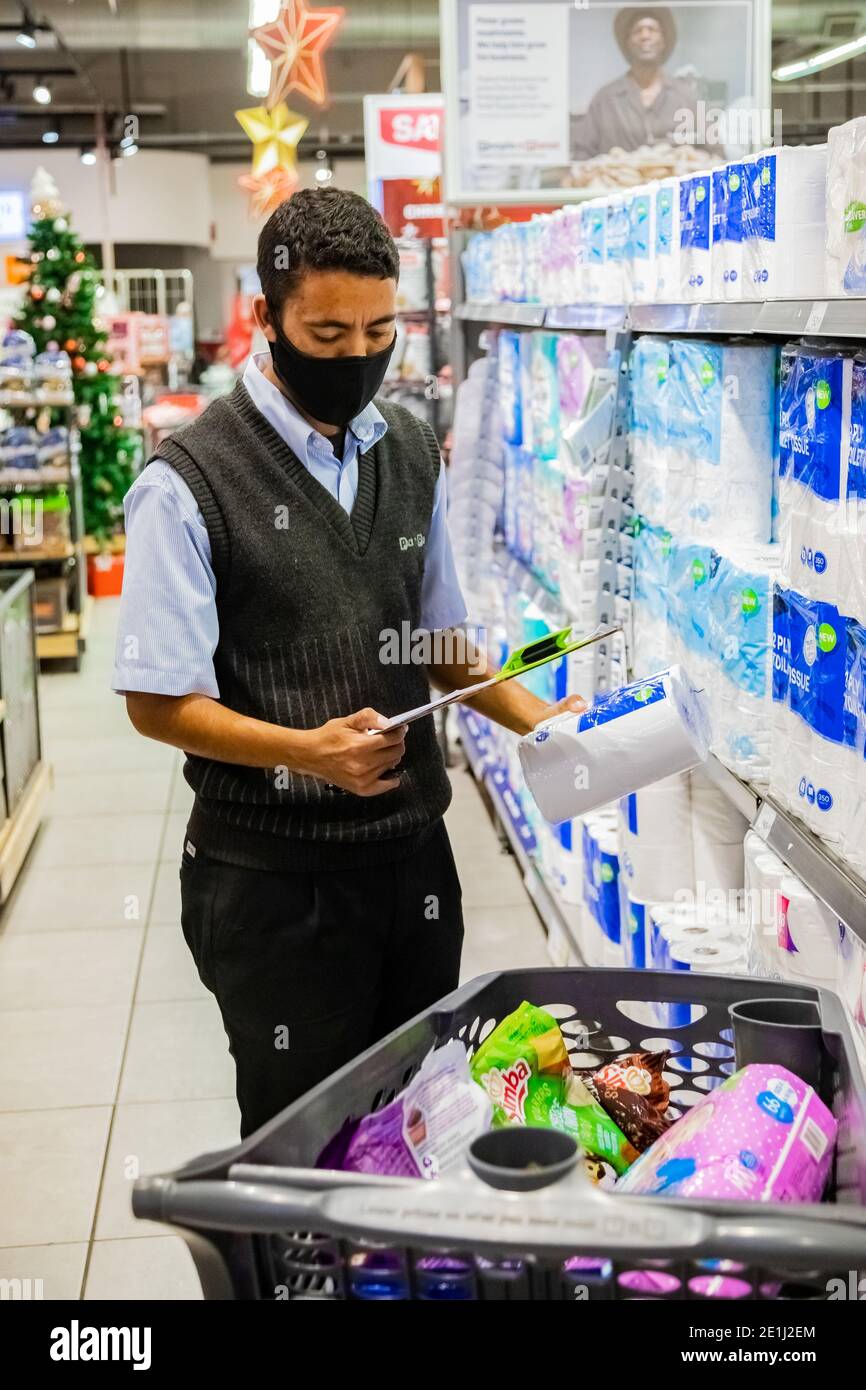 Cape Town, Afrique du Sud - 10 décembre 2020 : membre du personnel qui cueille les produits d'épicerie de l'étagère pour un service de livraison express à domicile au service local Pick n Pay su Banque D'Images