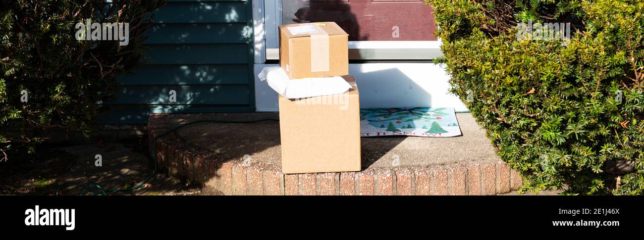 Les forfaits livrés et déposés sur une maison résidentielle avant de stoop laissé dehors dans l'ouverture pour tous à voir et à prendre pendant la période des fêtes de Noël. Banque D'Images Les forfaits livrés et déposés sur une maison résidentielle avant de stoop laissé dehors dans l'ouverture pour tous à voir et à prendre pendant la période des fêtes de Noël. Banque D'Images