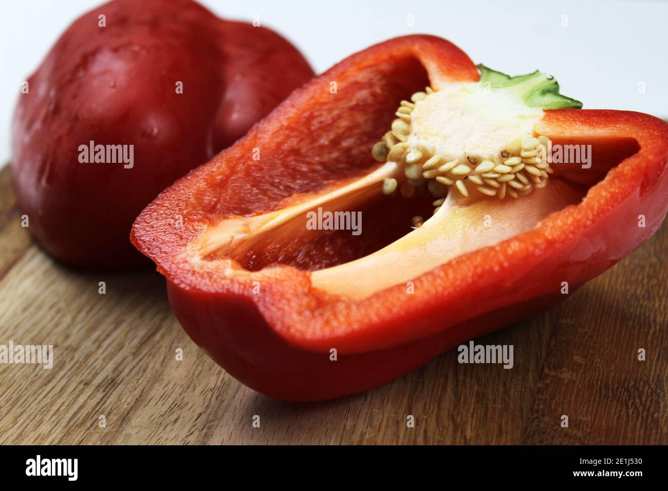 Un poivron rouge sur une planche à découper en bois sur fond blanc Uni. Banque D'Images