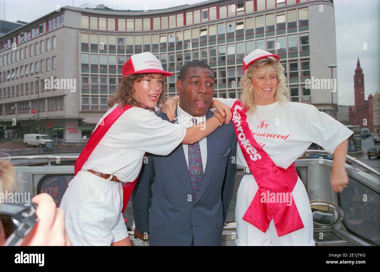 Frank Bruno ouvre un nouveau Ladbrokes dans le centre-ville de Birmingham en juillet 1990 avec la compagnie de deux filles promotionnelles pour faire connaître l'événement. Banque D'Images