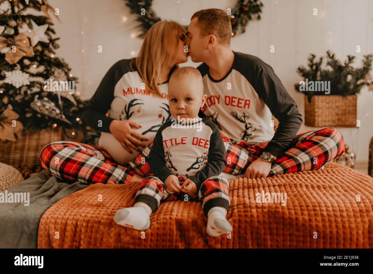 joyeux famille en pyjama avec un enfant embrassant sur le lit dans la chambre. vêtements pour la famille du nouvel an tendance ensembles. Fête de la Saint-Valentin GI Banque D'Images