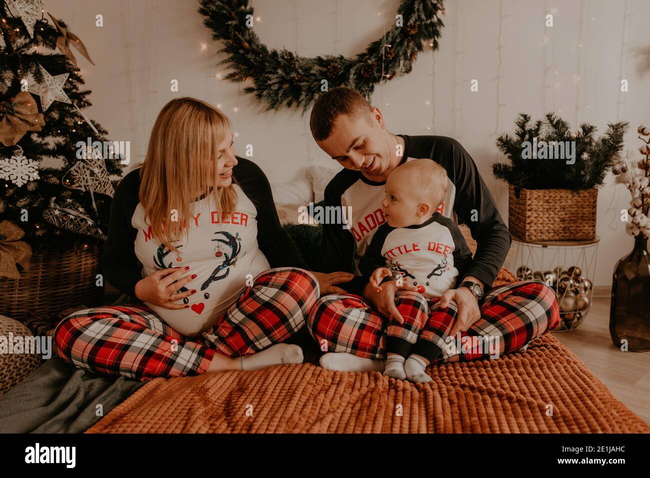 joyeux famille en pyjama avec enfant sur le lit de la chambre. vêtements pour la famille du nouvel an looks ensembles. Cadeaux pour la Saint-Valentin Banque D'Images