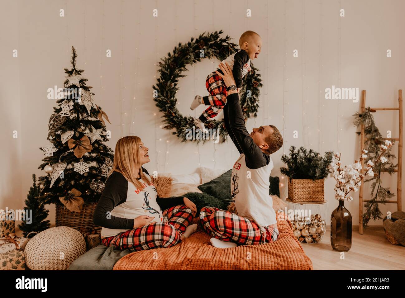 joyeux famille en pyjama avec un enfant embrassant sur le lit dans la chambre. vêtements pour la famille du nouvel an tendance ensembles. Fête de la Saint-Valentin GI Banque D'Images