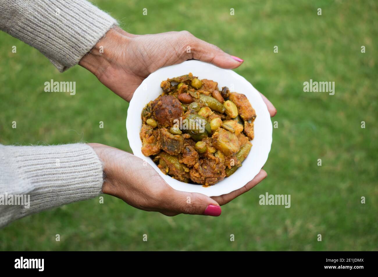 Undhiyu ou Oondhiyu un plat traditionnel célèbre de la cuisine gujarati servi dans un bol. Femme tenant la main undhiyu. Uttarayan kite festival gain spécial Banque D'Images