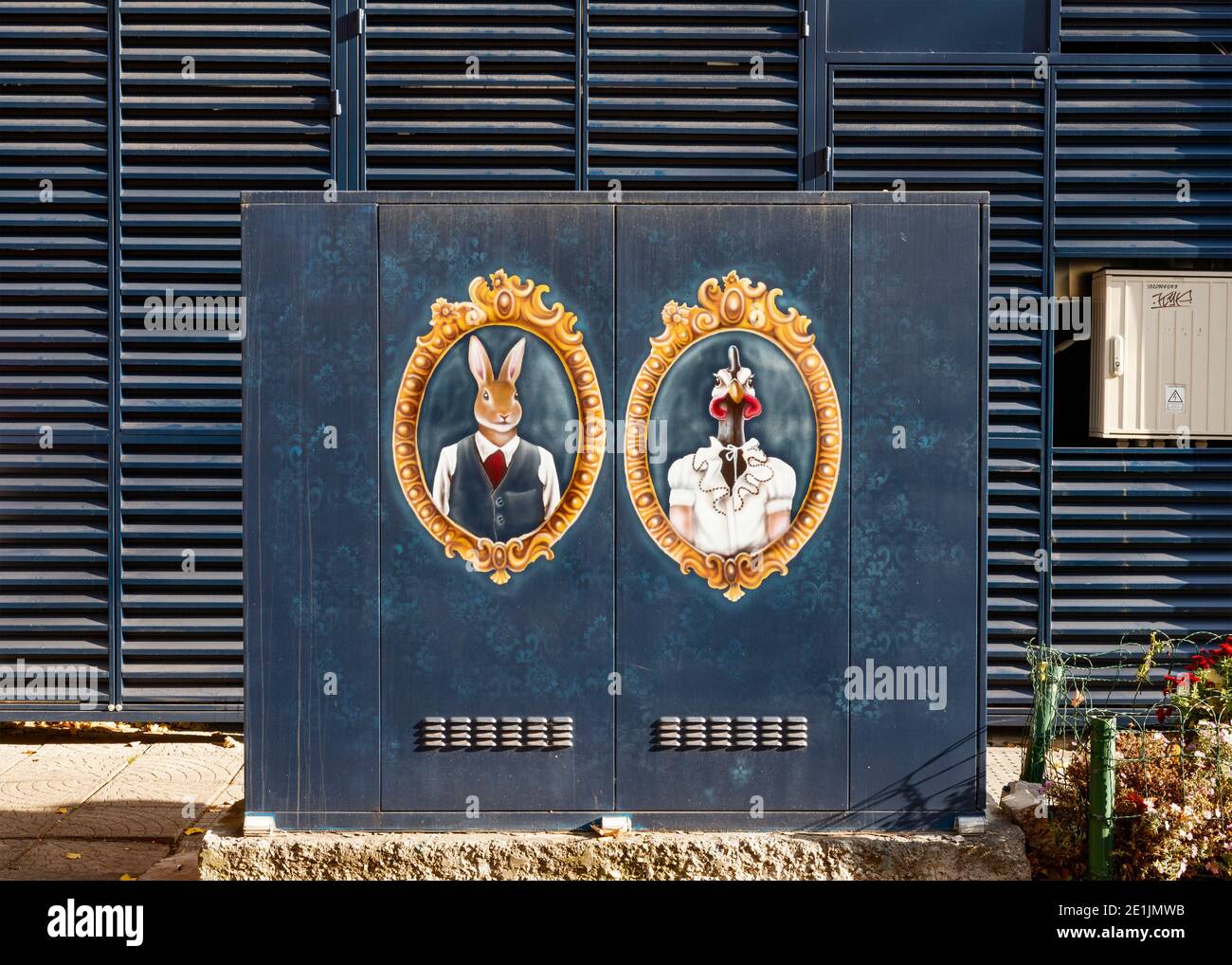 Graffiti Street art peinture colorée sur boîte électrique en métal représentant des portraits encadrés vintage de lapin humanisé habillé et de poule sur le bleu Banque D'Images
