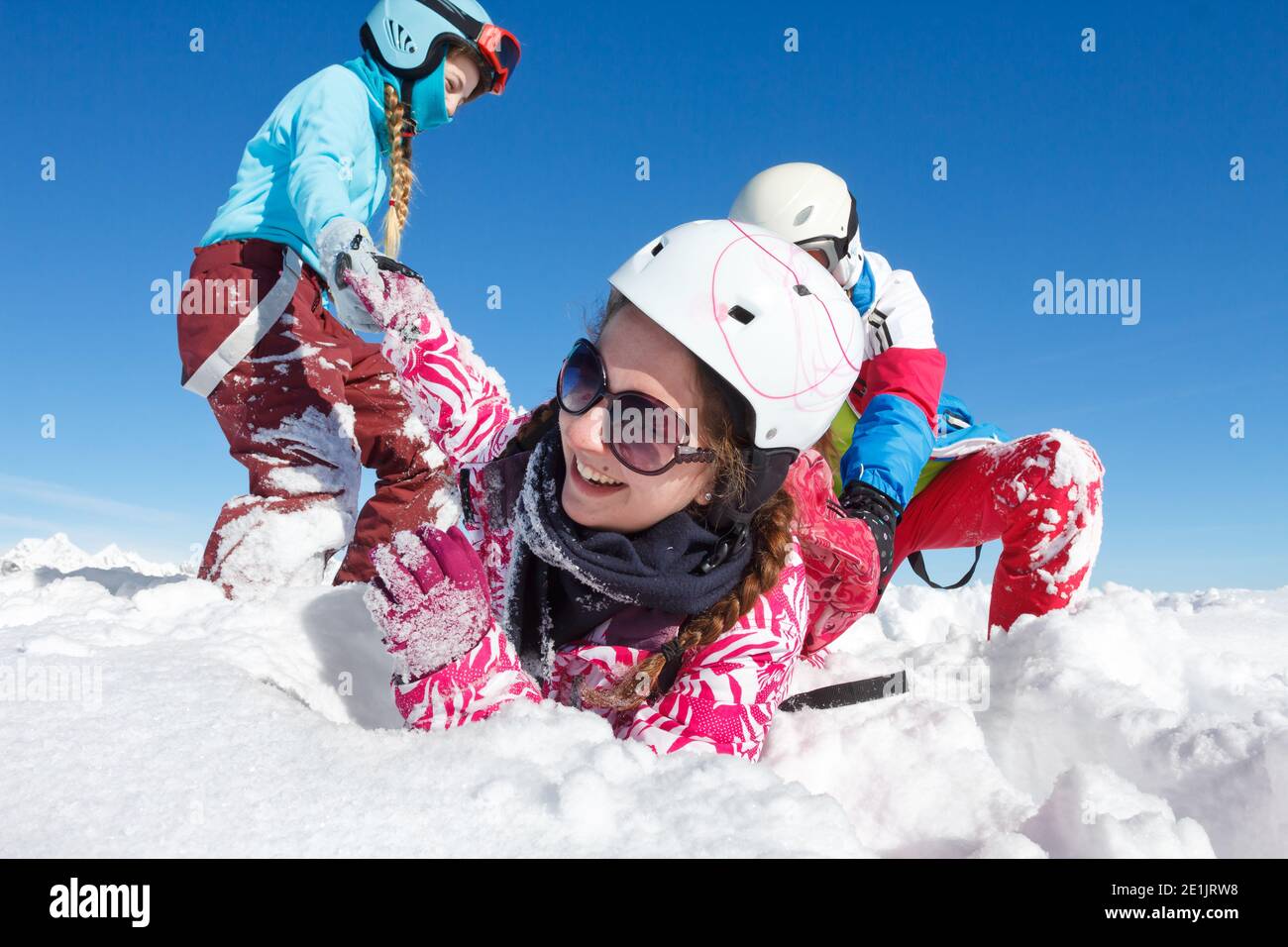 Gros plan sur les jeunes filles avec des vêtements colorés jouant dans frais neige sur les pistes de ski et ciel bleu dans les montagnes Banque D'Images