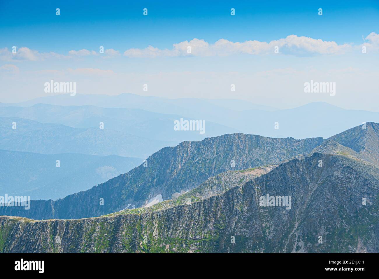 Vallée de montagne avec crête en pierre et arbres à l'horizon. Traversez les rochers sauvages en été. Paysage de montagne par rapport au ciel bleu le jour ensoleillé Banque D'Images