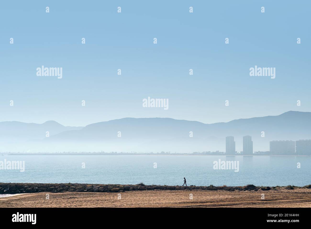 Plage de sable vide et silhouette de la ville de Cullera. Vue sur la mer Méditerranée, ciel nuageux et paysage brumeux et brumeux. Province Banque D'Images