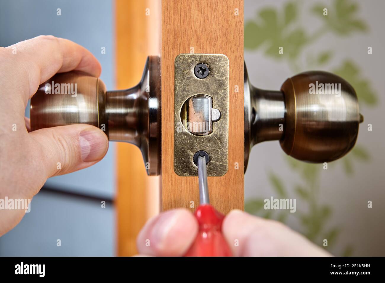 En posant la poignée de porte avec le verrou, le serrurier fixe le boulon  sur la plaque de verrouillage Photo Stock - Alamy