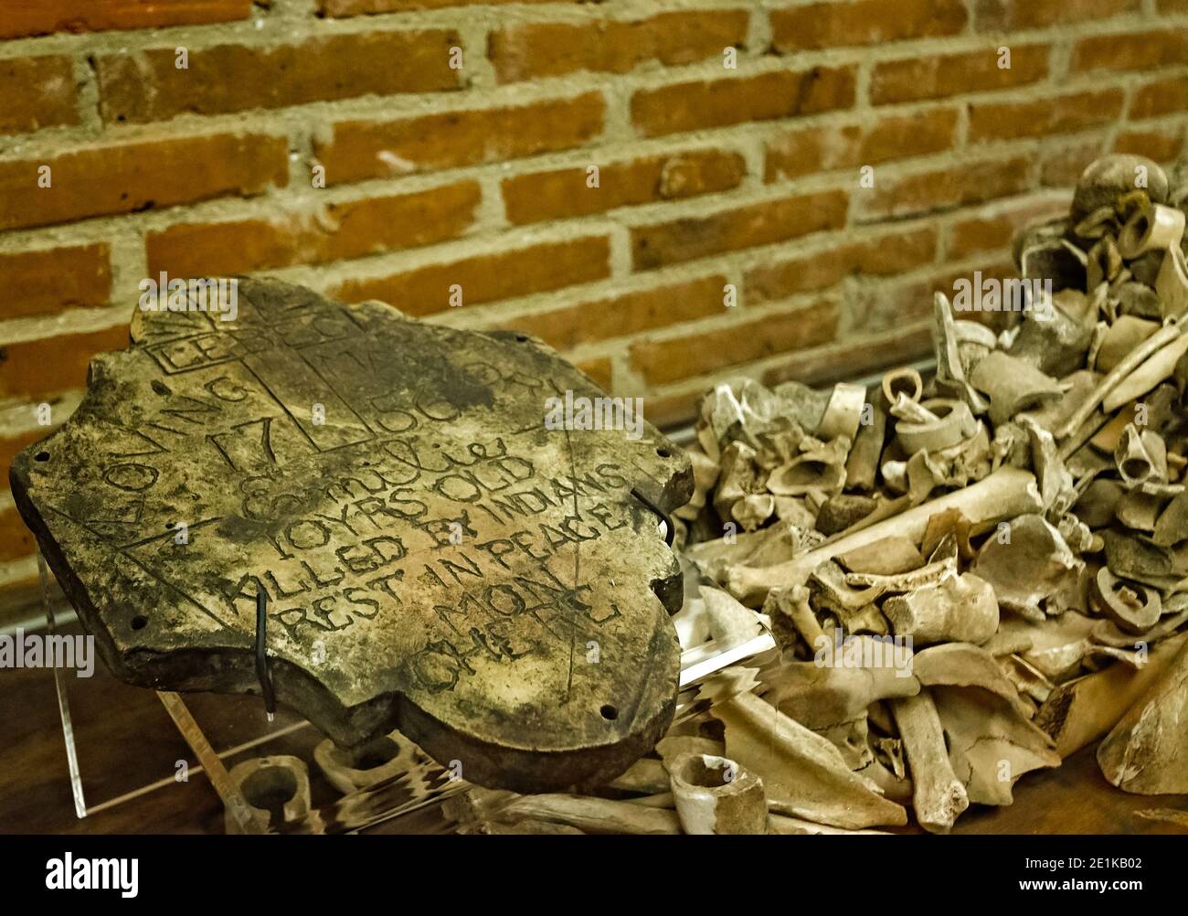 Une pierre tombale antique d'un ancien colon est exposée avec des os et d'autres objets trouvés au fort de Colonial Mobile à Mobile, Alabama. Banque D'Images