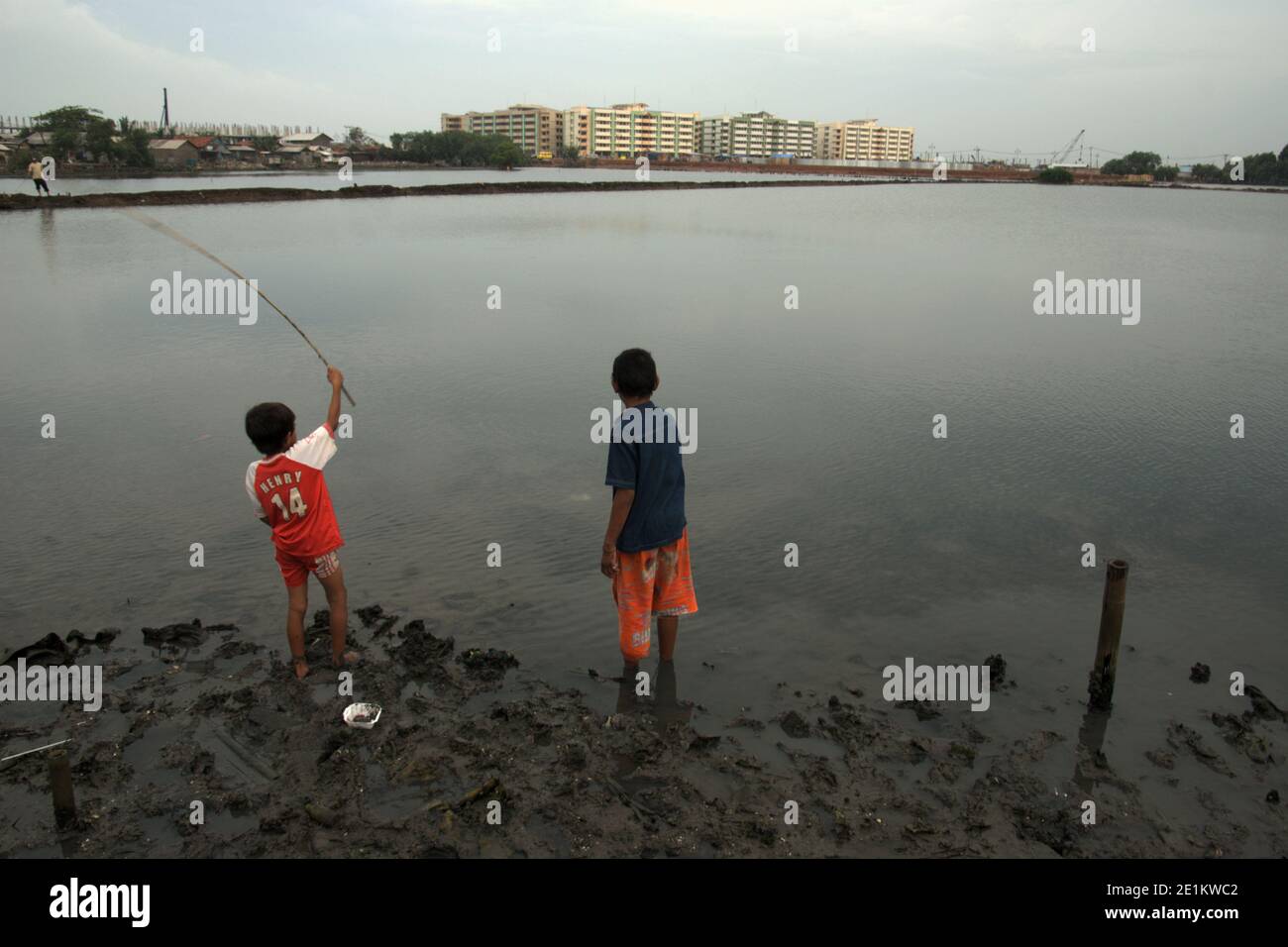 Enfants pêchant dans un marais saumâtre intérieur en partie utilisé comme ferme piscicole dans la zone côtière du nord de Jakarta, Jakarta, Indonésie. Banque D'Images