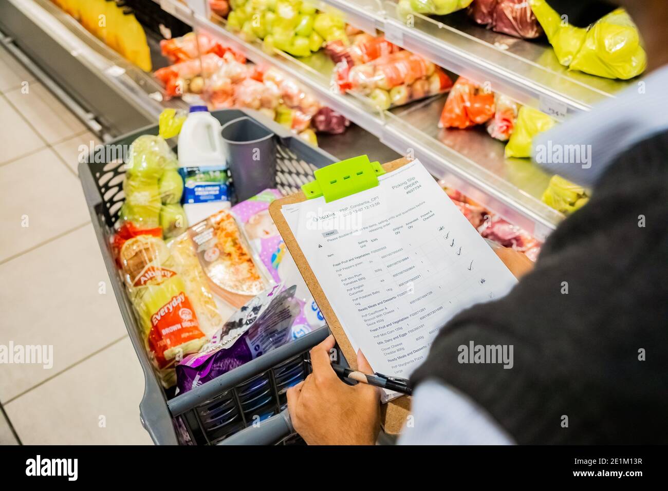 Cape Town, Afrique du Sud - 10 décembre 2020 : membre du personnel qui cueille les produits d'épicerie de l'étagère pour un service de livraison express à domicile au service local Pick n Pay su Banque D'Images