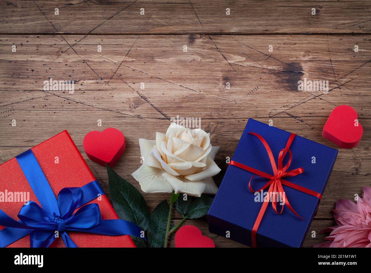 Boîtes cadeau ou cadeau avec ruban rouge et bleu noeud, coeurs et fleurs sur fond de bois pour la Saint Valentin. Espace copie vue de dessus plat Banque D'Images Boîtes cadeau ou cadeau avec ruban rouge et bleu noeud, coeurs et fleurs sur fond de bois pour la Saint Valentin. Espace copie vue de dessus plat Banque D'Images