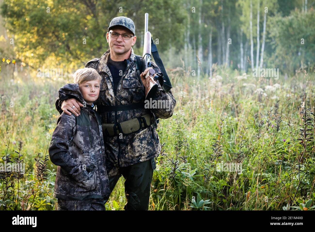 Père et fils marchant ensemble à l'extérieur avec une carabine pour la chasse Banque D'Images