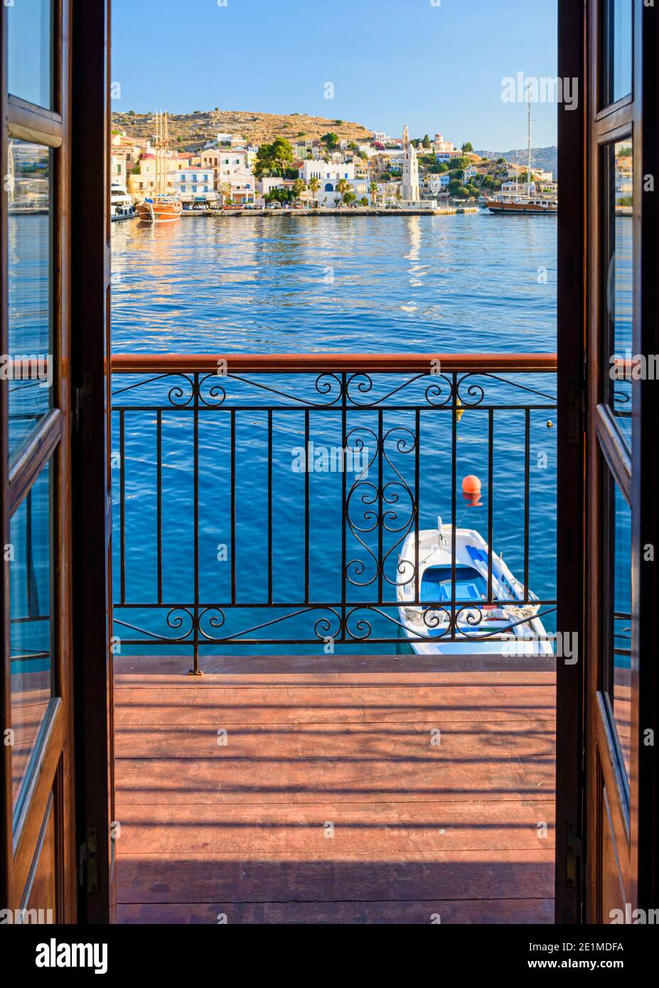 Vue à travers un balcon en fer forgé de la ville de Gialos et de la baie de Symi, l'île de Symi, Dodécanèse, Grèce Banque D'Images