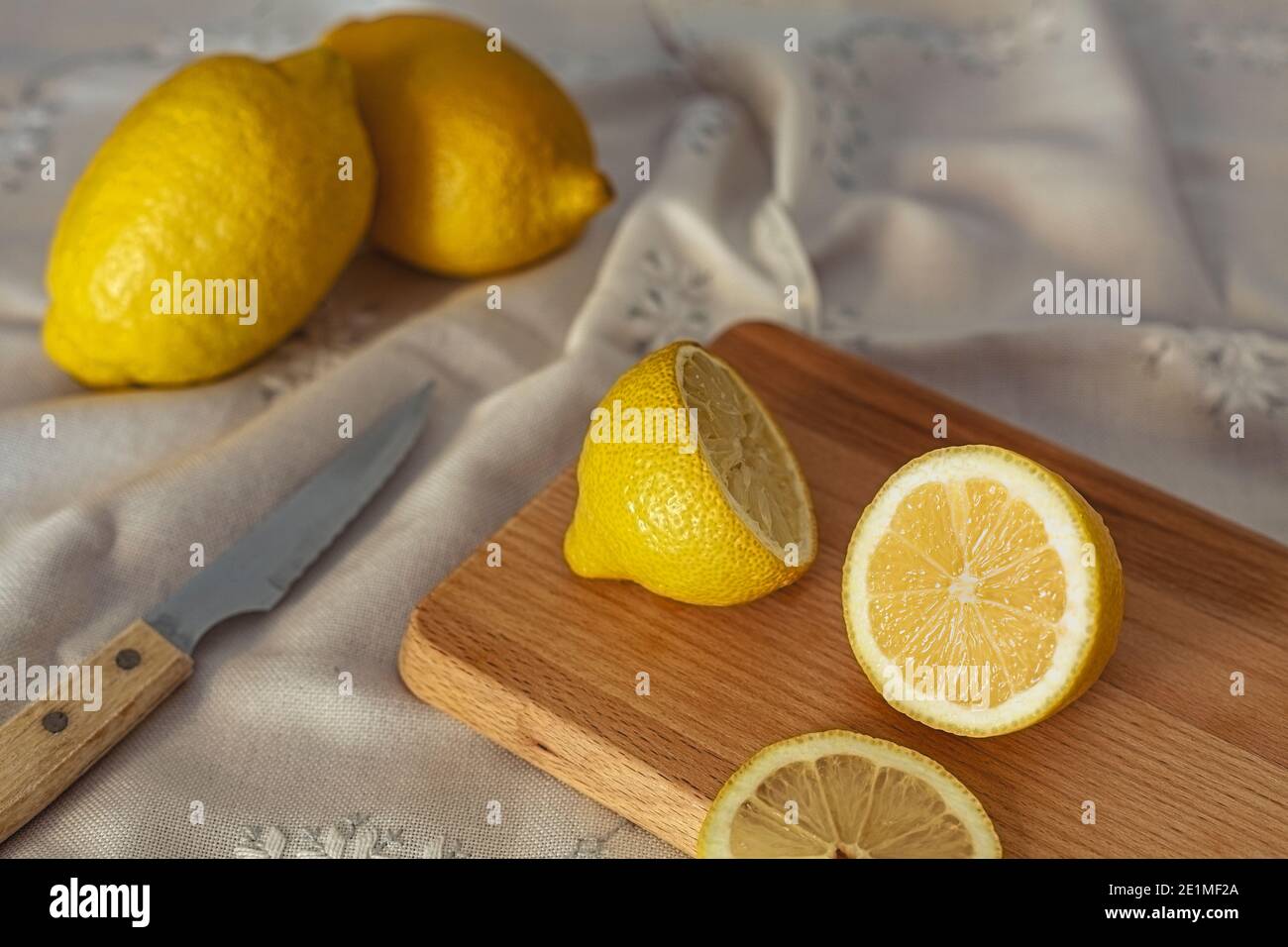 Un gros plan de citrons coupés sur une planche de bois la table est recouverte d'une nappe Banque D'Images