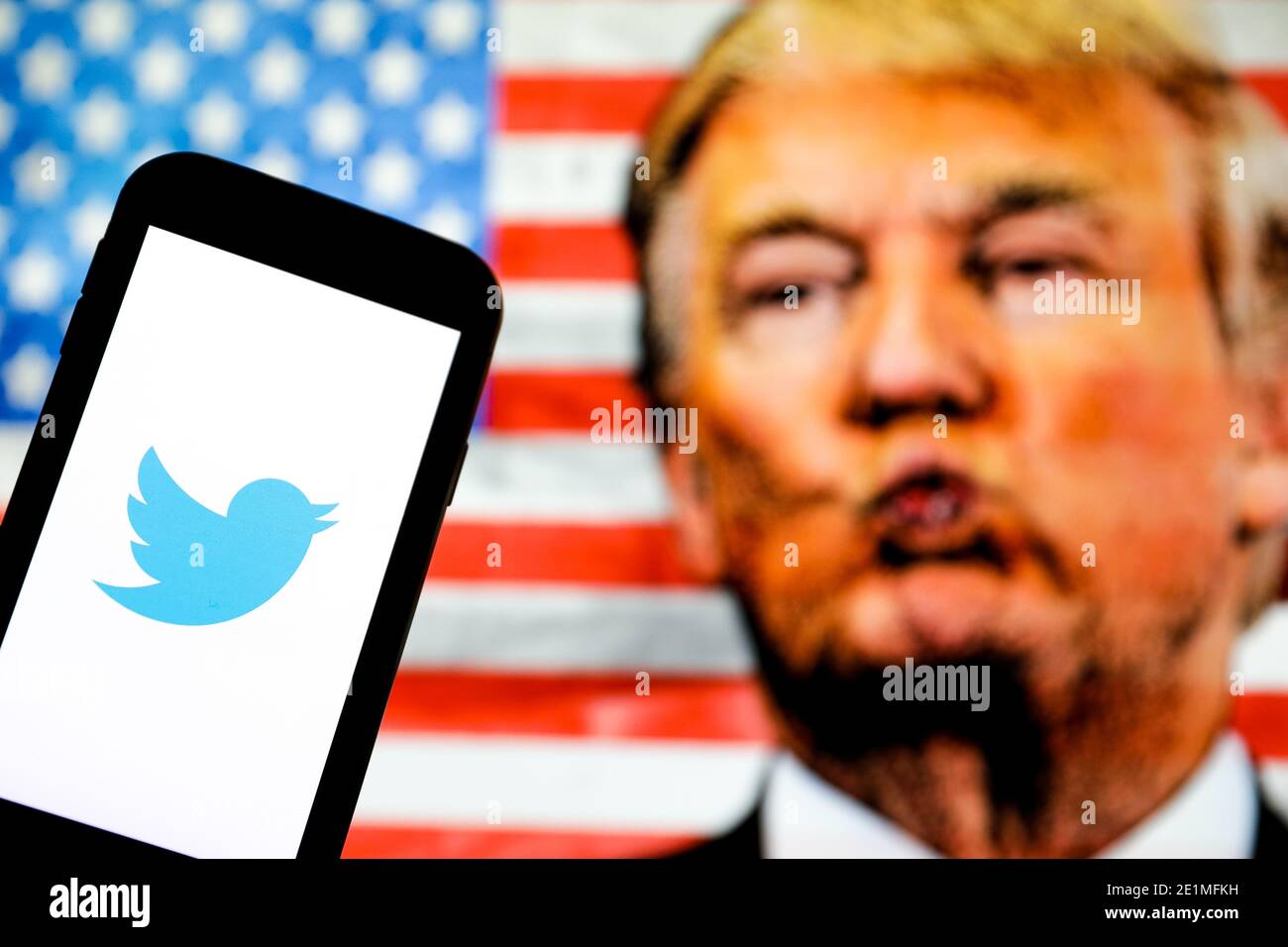 Dans cette illustration photo, le logo de la société apparaît sur un smartphone. Un visage de Donald Trump et le drapeau des États-Unis d'Amérique sont visibles moi Banque D'Images