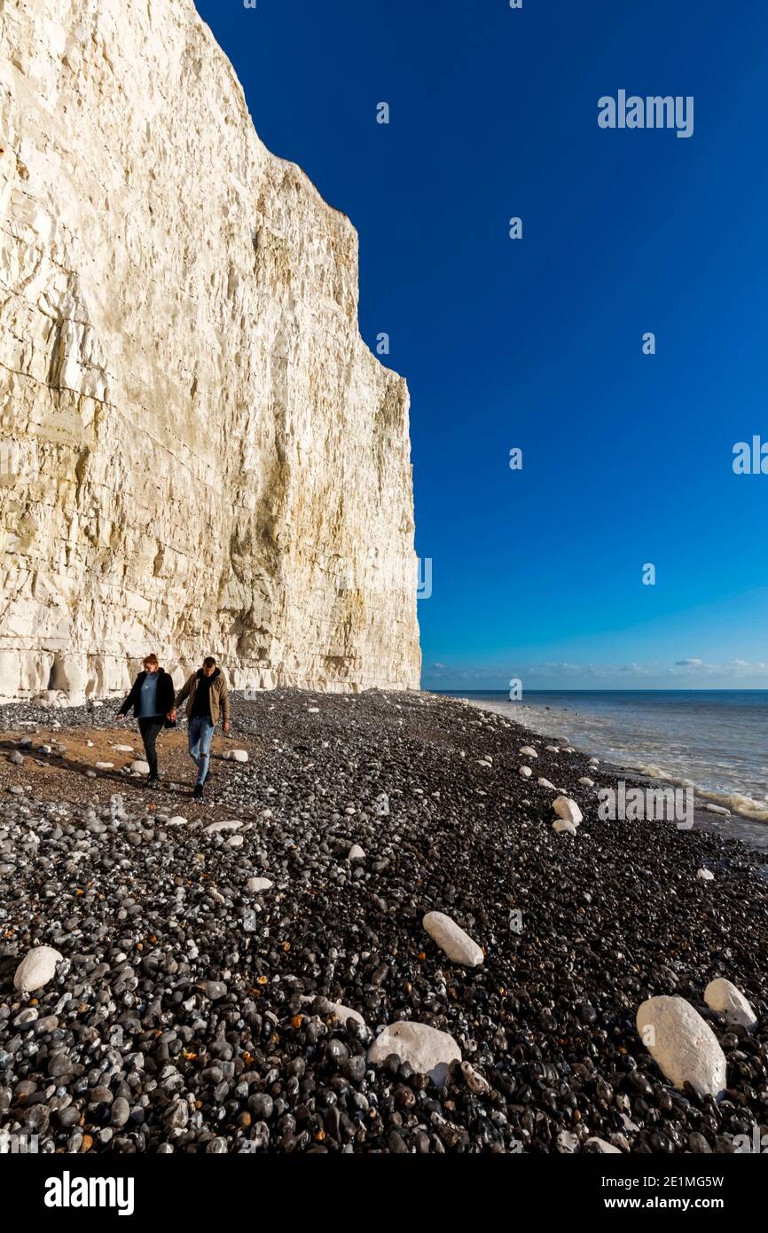 Angleterre, East Sussex, Eastbourne, Birling Gap, les Seven Sisters Cliffs et la plage avec couple de marche à la base des falaises Banque D'Images