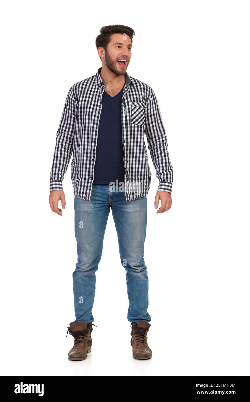 Joyeux homme décontracté dans une chemise de bûcheron sans bouton est debout, regardant loin et criant. Vue avant. Prise de vue en studio sur toute la longueur isolée sur blanc. Banque D'Images