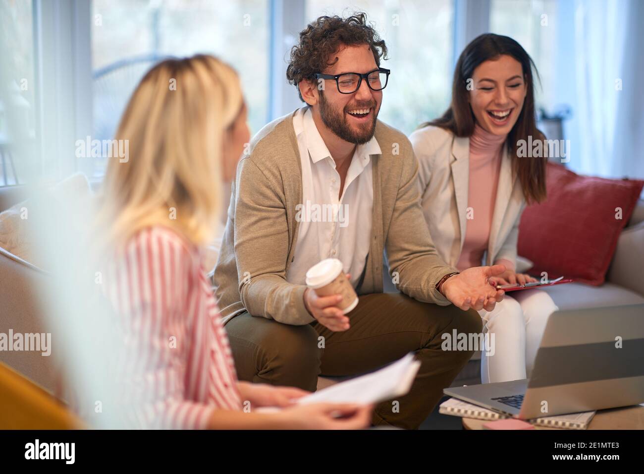Un homme d'affaires élégant à une réunion dans une atmosphère détendue ayant un bon moment avec ses collègues féminins. Personnes, affaires, réunion Banque D'Images