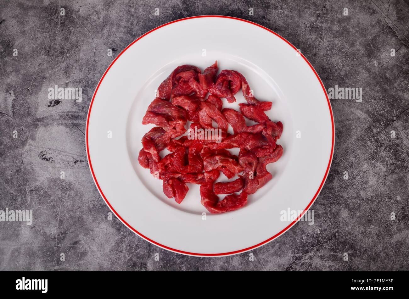 Viande de bœuf crue coupée en fines bandes pour le bœuf Stroganoff sur la plaque blanche Banque D'Images