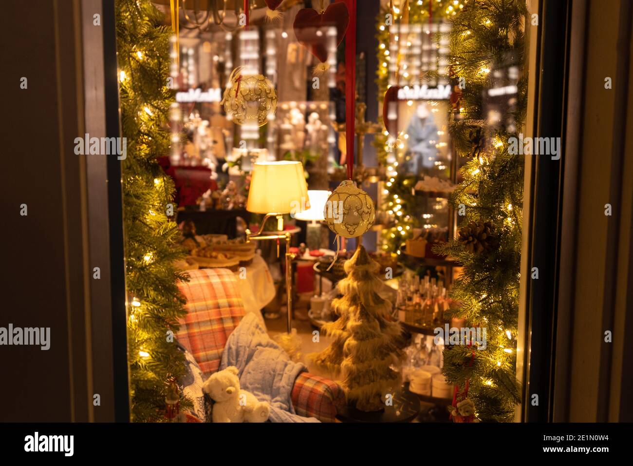 Fenêtre réfléchissante avec vue de l'extérieur dans une chambre charmante. Canapé confortable avec décoration de Noël dans des lumières chaudes. Concept pour la chambre de Noël. Banque D'Images