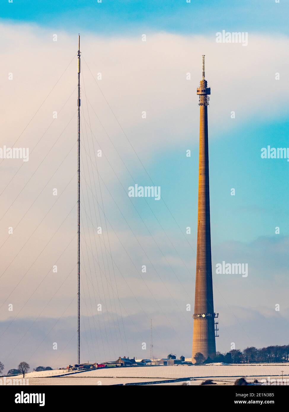 Mât Emley Moor avec mât temporaire le long du côté dans le village enneigé du West Yorkshire d'Emley. Banque D'Images