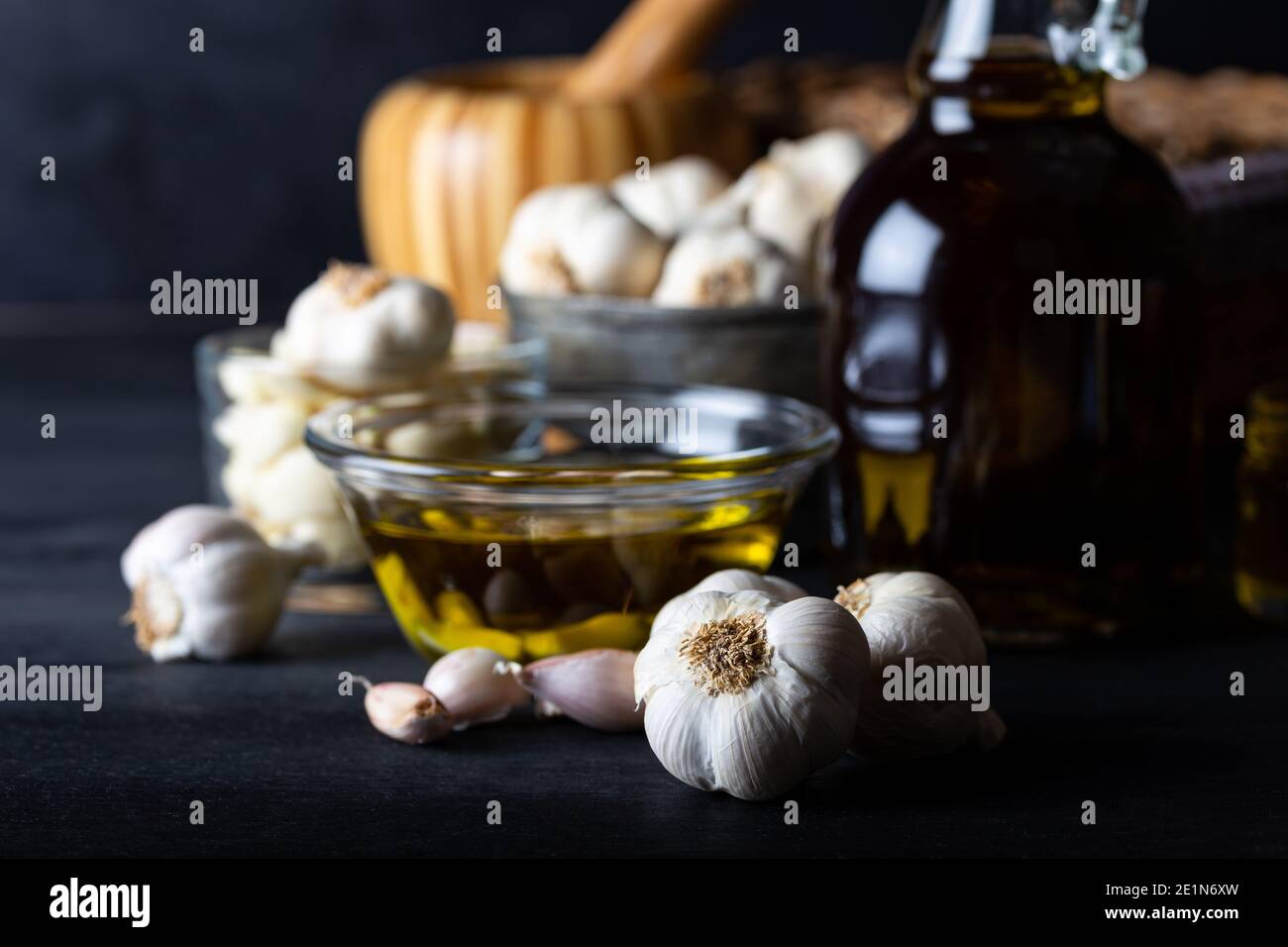 Huile d'ail et d'ail mûrs et crus dans un verre de bouteille sur fond de bois foncé. Garlics et huile d'olive. Banque D'Images