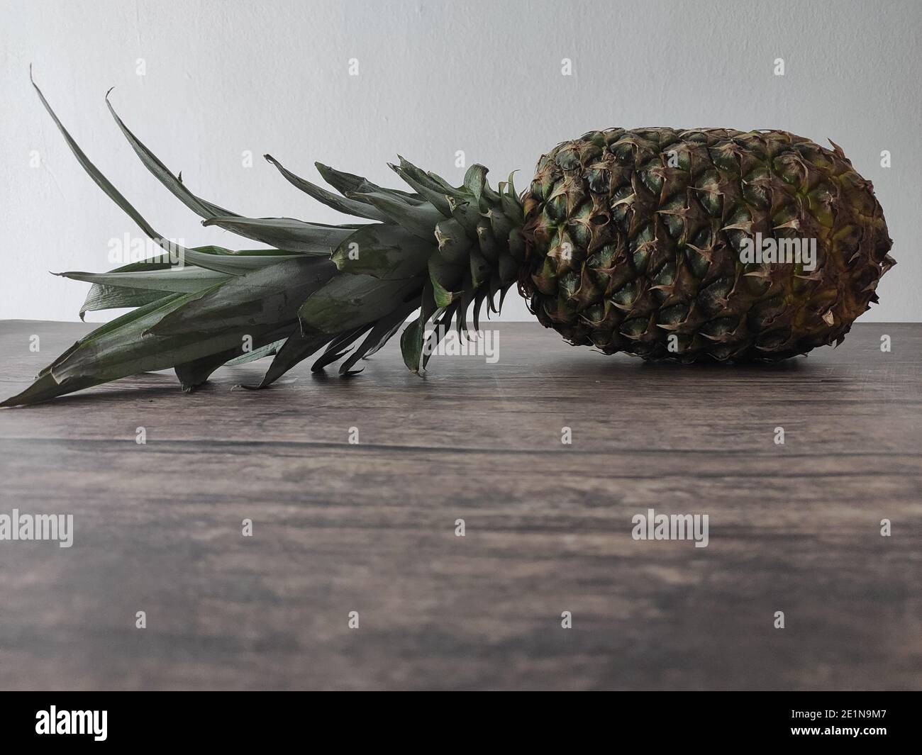 Un ananas entier posé sur une table en bois Banque D'Images