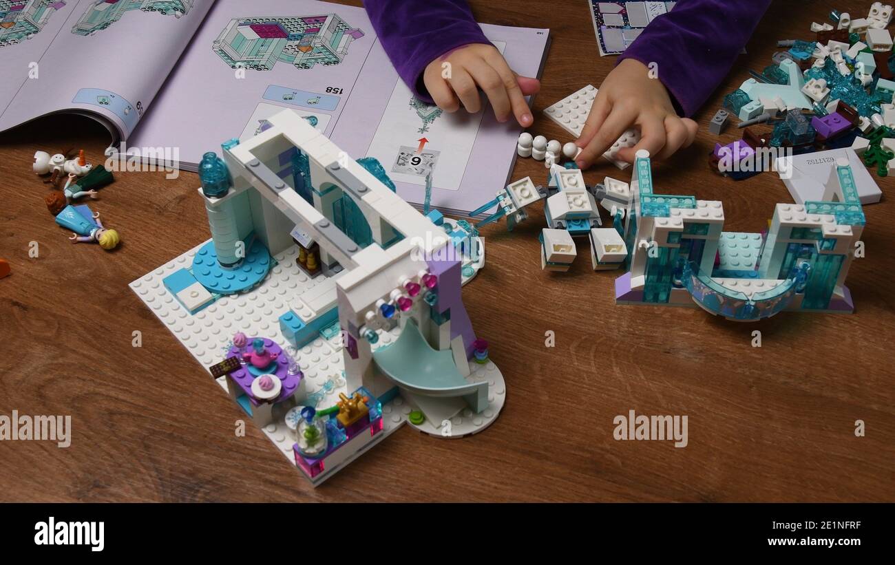 Les mains des enfants jouent avec le jouet en plastique Lego bonhomme de neige et des blocs de construction de dessin animé de Disney gelé. Les doigts de petite fille prennent et mettent des jouets dans une rangée. Intelligent Banque D'Images