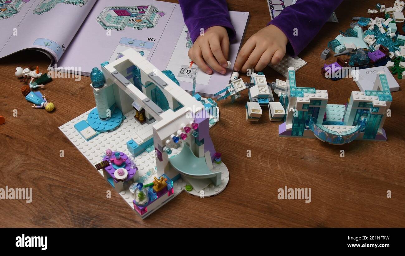 Les mains des enfants jouent avec le jouet en plastique Lego bonhomme de  neige et des blocs de construction de dessin animé de Disney gelé. Les  doigts de petite fille prennent et