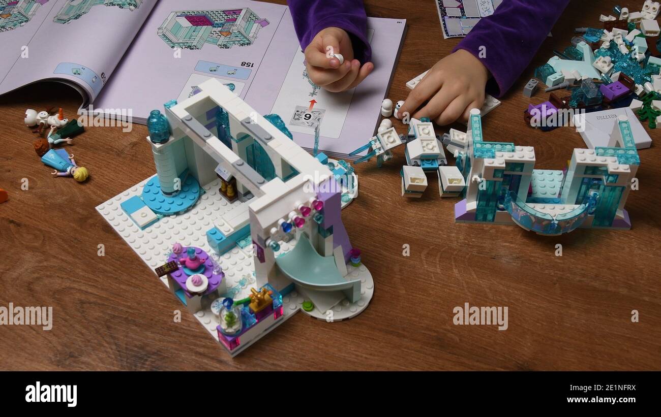 Les mains des enfants jouent avec le jouet en plastique Lego bonhomme de neige et des blocs de construction de dessin animé de Disney gelé. Les doigts de petite fille prennent et mettent des jouets dans une rangée. Intelligent Banque D'Images