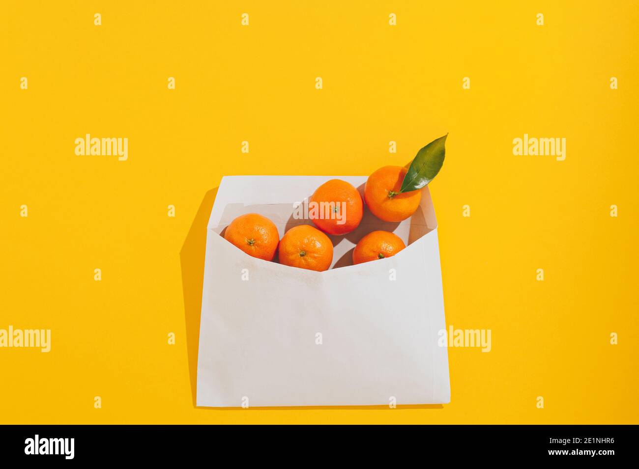 Mise en page créative réalisée avec des mandarines orange fraîches dans une enveloppe en papier sur fond jaune. Concept zéro déchet. Arrière-plan abstrait été ou hiver Banque D'Images