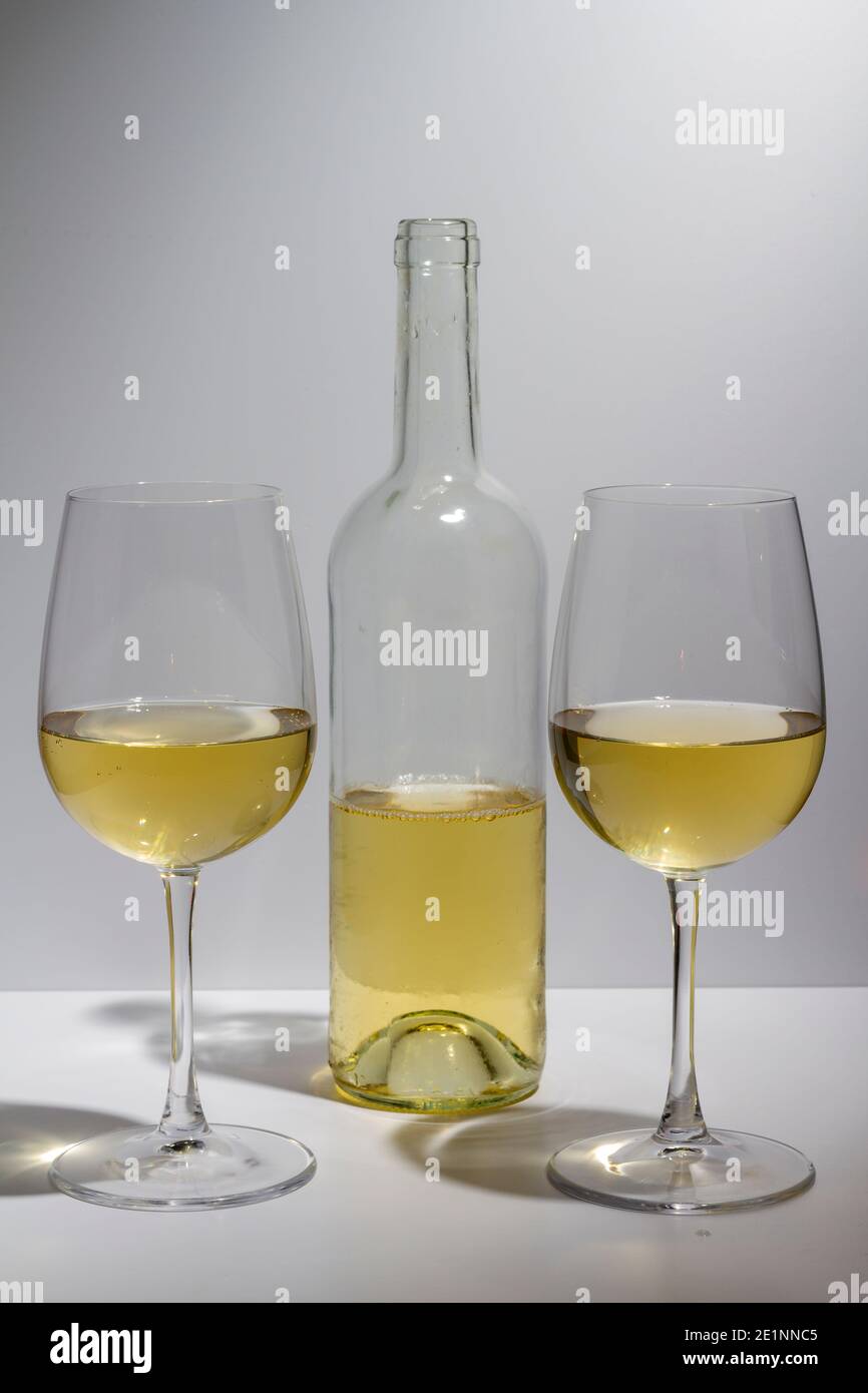 Bouteille transparente avec vin blanc à l'intérieur et deux verres avec vin blanc sur fond blanc. Banque D'Images Bouteille transparente avec vin blanc à l'intérieur et deux verres avec vin blanc sur fond blanc. Banque D'Images