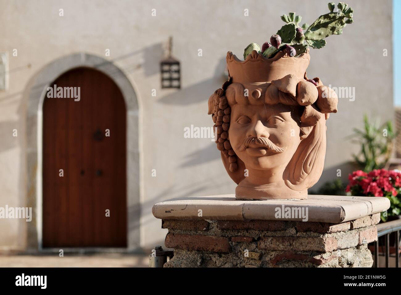 Hors foyer façade maison de la Sicile se concentre sur un pot traditionnel en terre cuite en forme de tête mauresque, dans le pot cultiver les fruits d'une poire piqueuse Banque D'Images