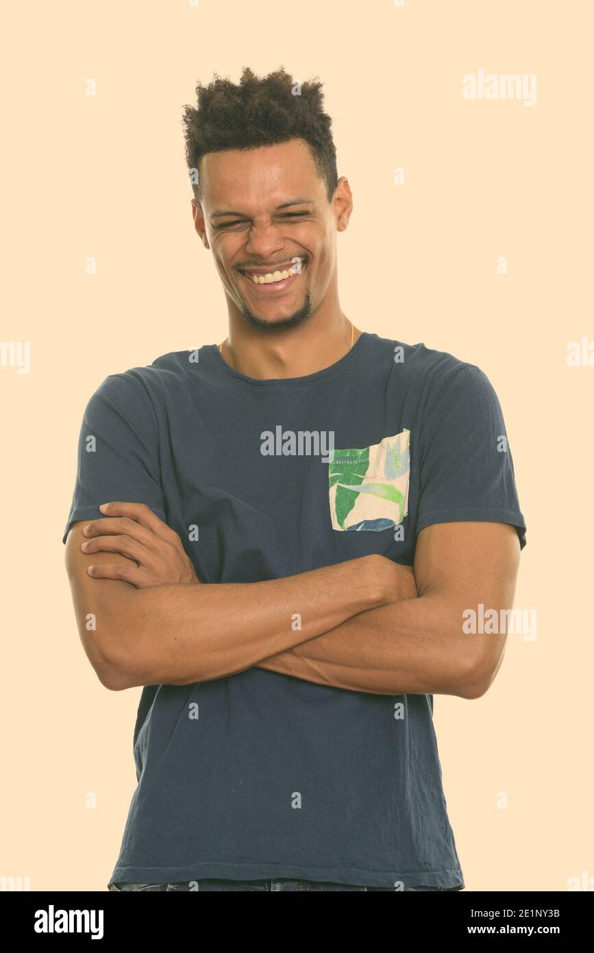 Studio shot of young happy African man smiling avec les bras croisés et les yeux fermés Banque D'Images