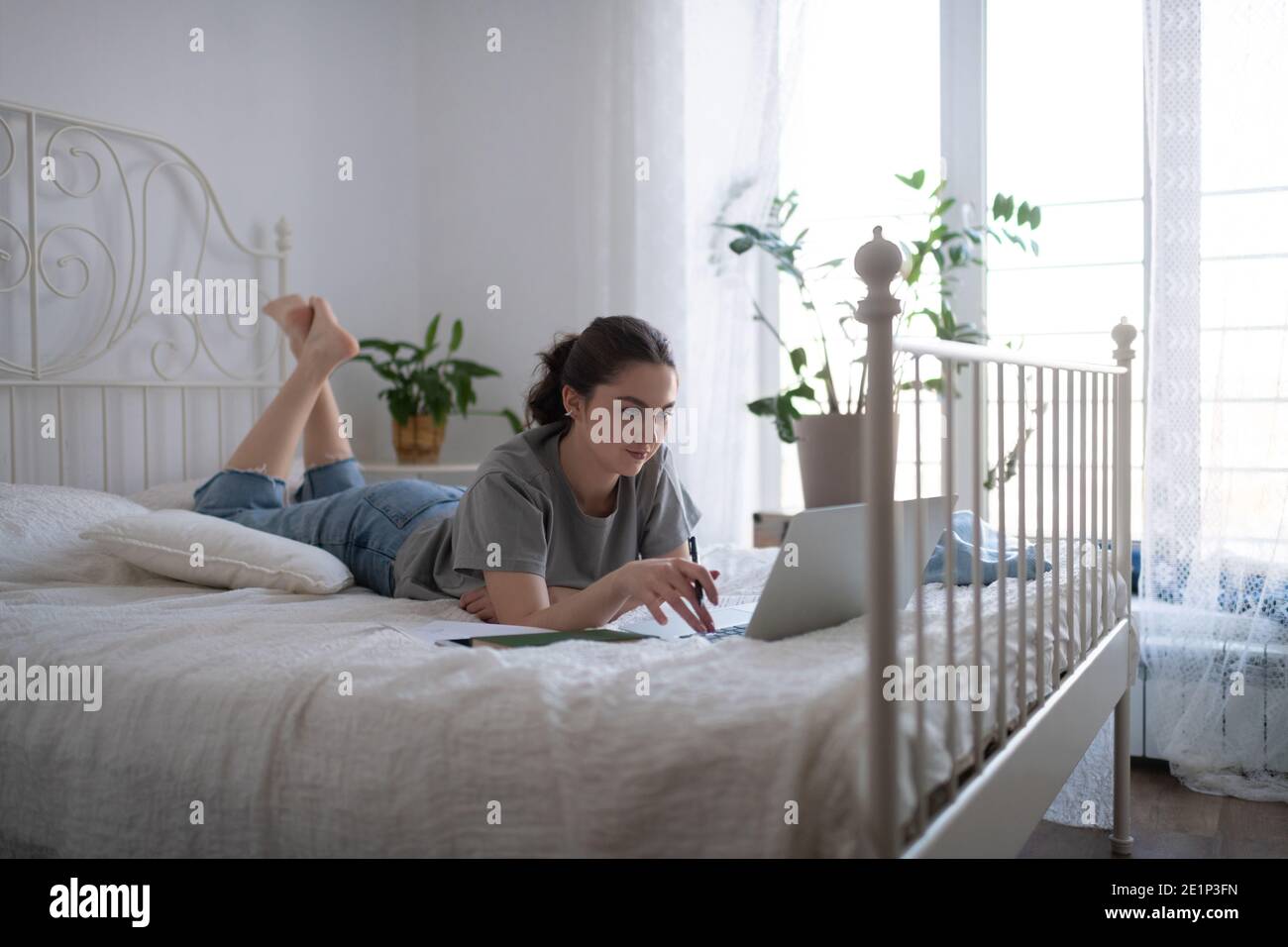 Une étudiante travaillant sur une affectation au lit pendant l'apprentissage à distance Banque D'Images