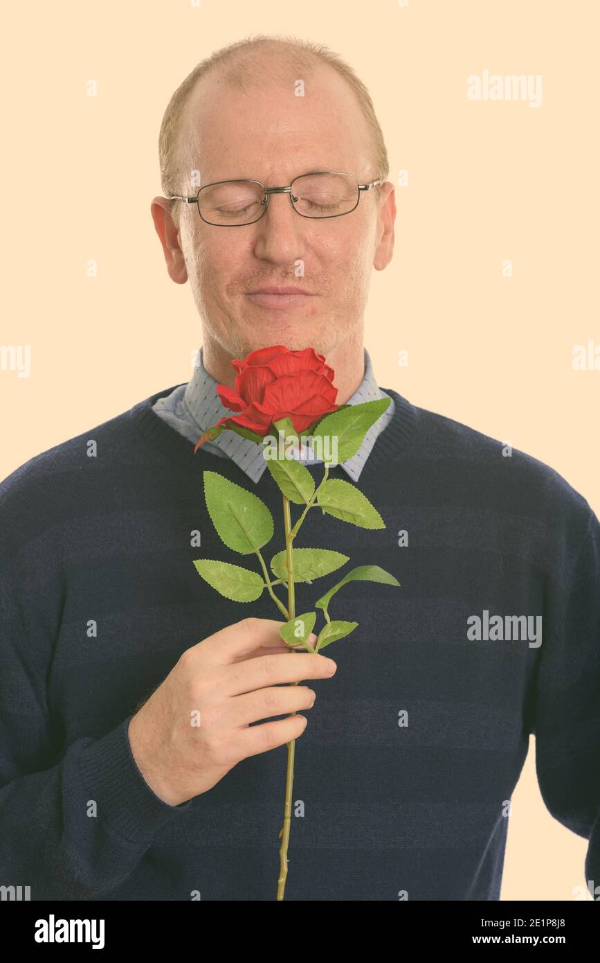 Studio shot of man smelling red rose avec les yeux fermé prêt pour la Saint-Valentin Banque D'Images