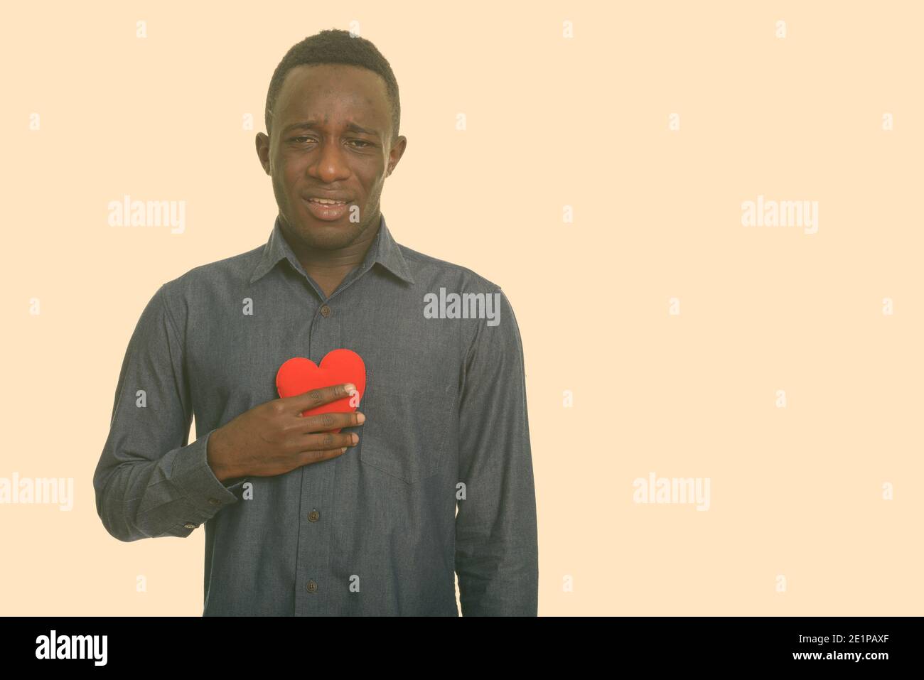 Sad Young African man holding cœur rouge sur la poitrine Banque D'Images