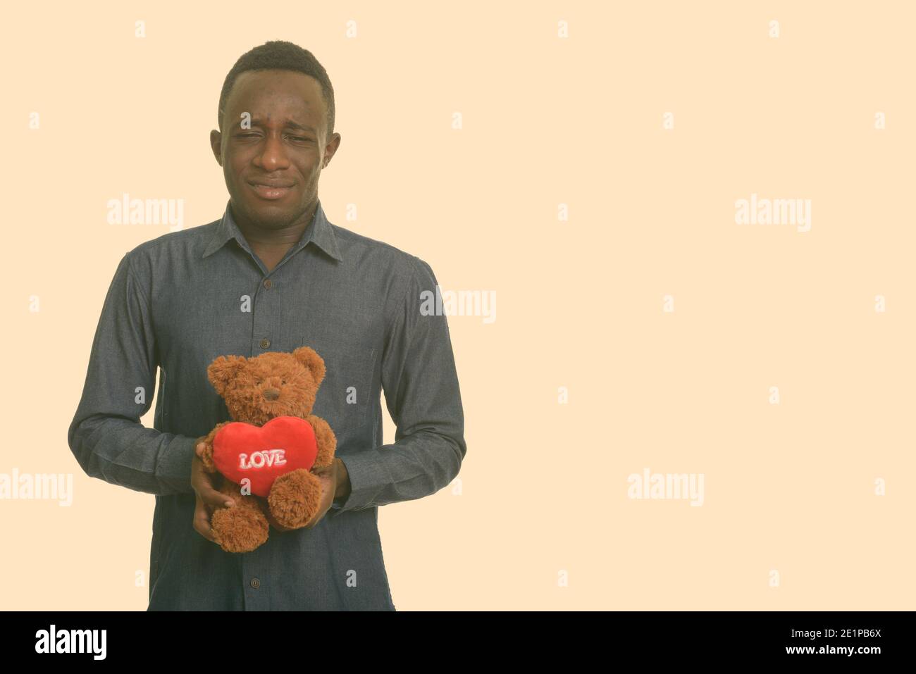 Beau jeune homme africain à la triste tout en maintenant l'ours en peluche avec coeur et amour sign Banque D'Images