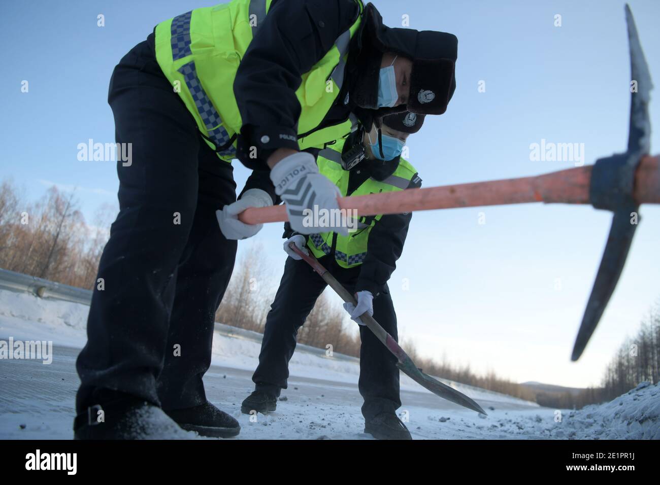 Dahinggan, province chinoise de Heilongjiang. 8 janvier 2021. Le policier Sun Chen (devant) et son collègue déglacer une route dans le district de Huzhong de Dahinggan, dans la province de Heilongjiang, au nord-est de la Chine, le 8 janvier 2021. Sun Chen a servi comme policier de la circulation pendant 35 ans. Dans le district de Huzhong, surnommé « la ville la plus froide de Chine », Sun a collé à son poste pour maintenir l'ordre de circulation. Il a pris son quart tôt le matin, en dépit du temps extrêmement froid avec la température la plus basse atteignant environ moins 40 degrés Celsius. Crédit : Wang Jianwei/Xinhua/Alay Live News Banque D'Images