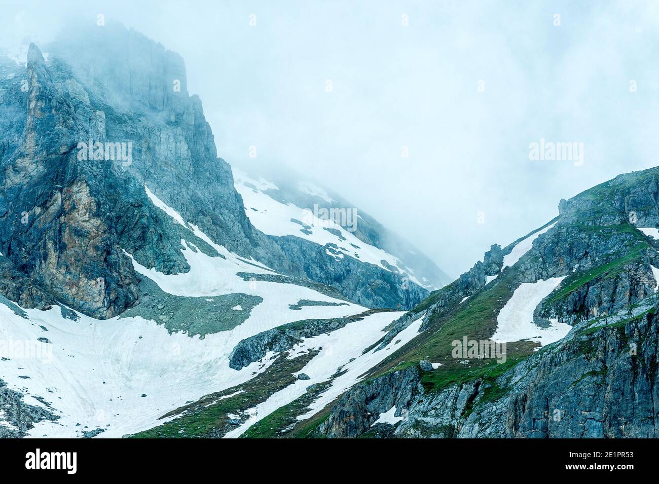 Mauvais temps dans les montagnes. Les nuages viennent de la vallée, assombrissant le ciel. Il reste quelques couches de neige sur les pistes. Banque D'Images