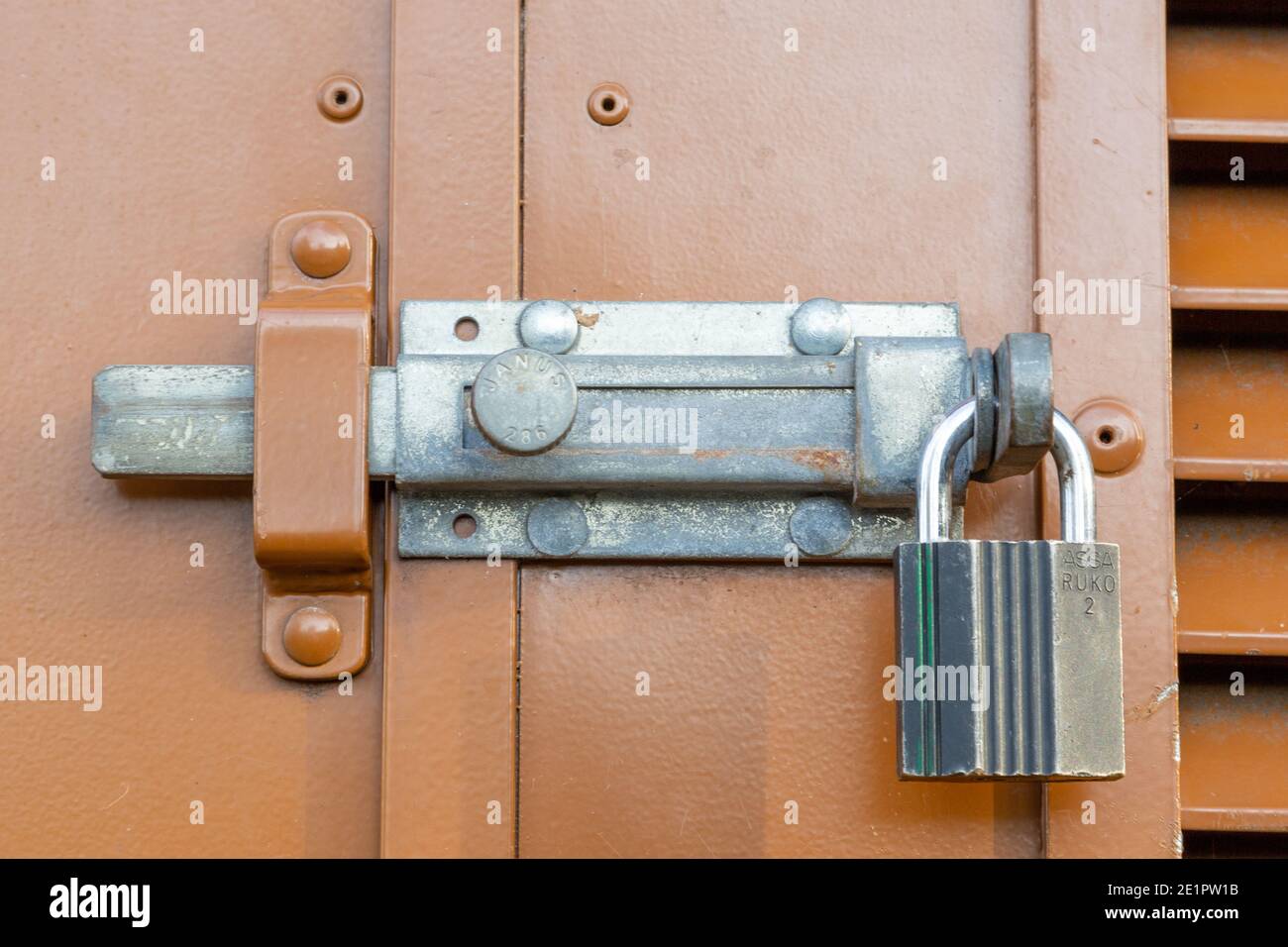 Un gros plan d'un verrou coulissant en métal et d'un cadenas à l'extérieur d'une porte Banque D'Images