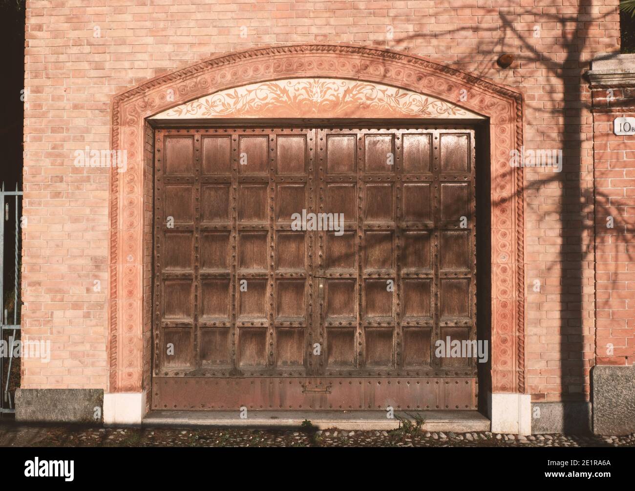 Garage dans une ancienne maison en brique avec grande porte d'accès en bois cloutée et cadre décoré.objet architectural externe de la structure de bâtiment. Banque D'Images