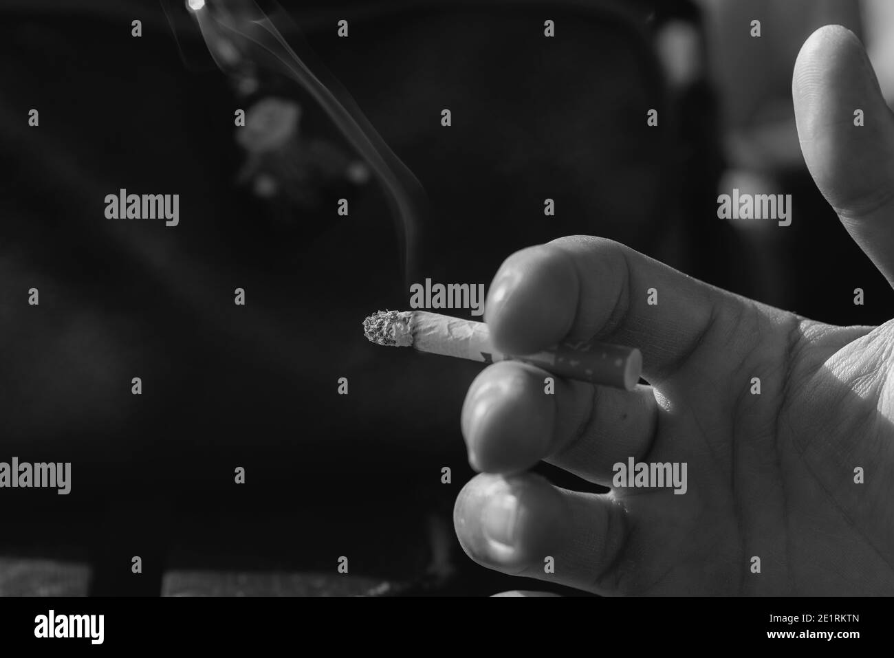 une cigarette, une cigarette entre deux doigts, une photo en noir et blanc Banque D'Images