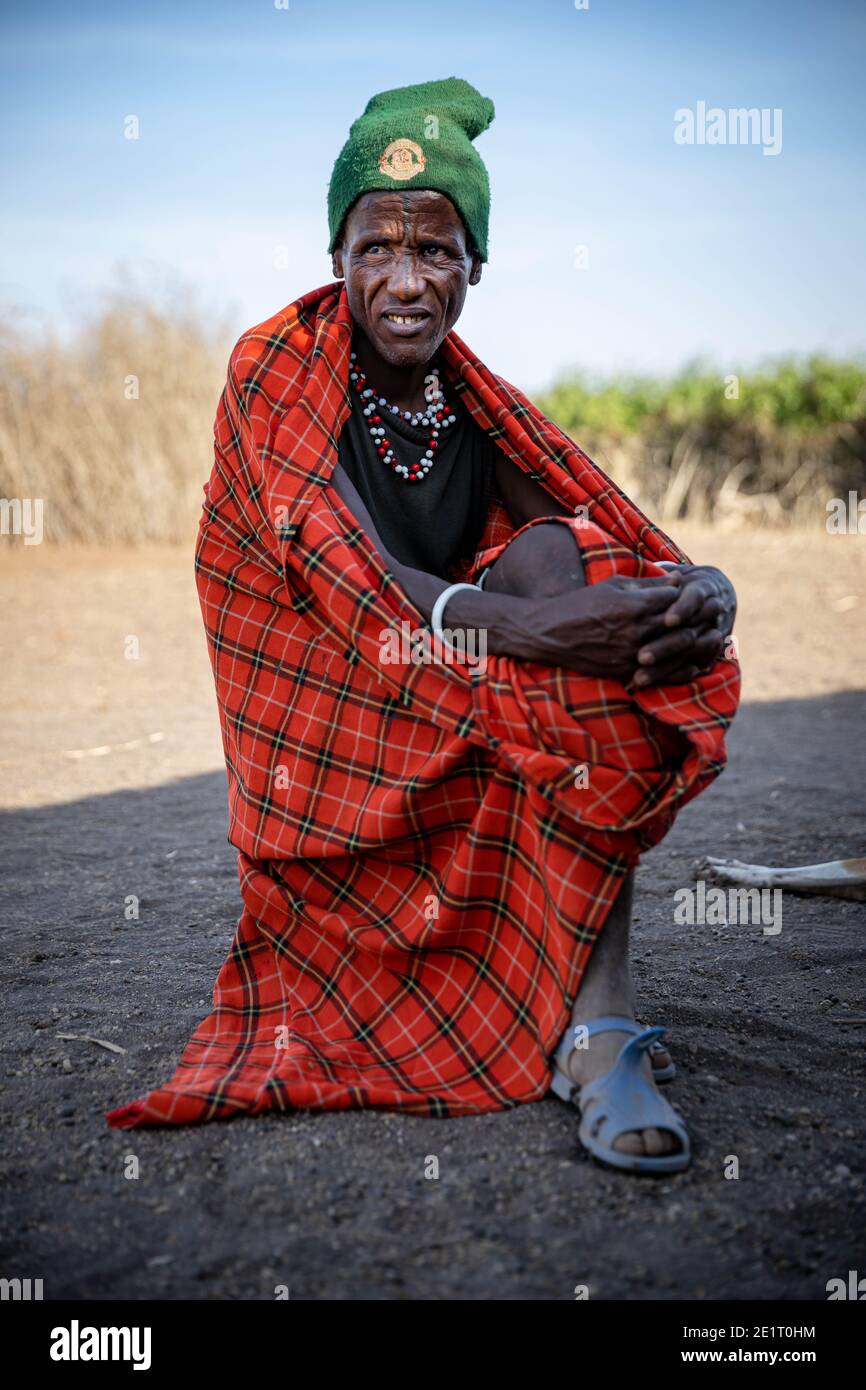 Ancien homme de Datoga assis à l'extérieur de sa maison dans des vêtements traditionnels Banque D'Images